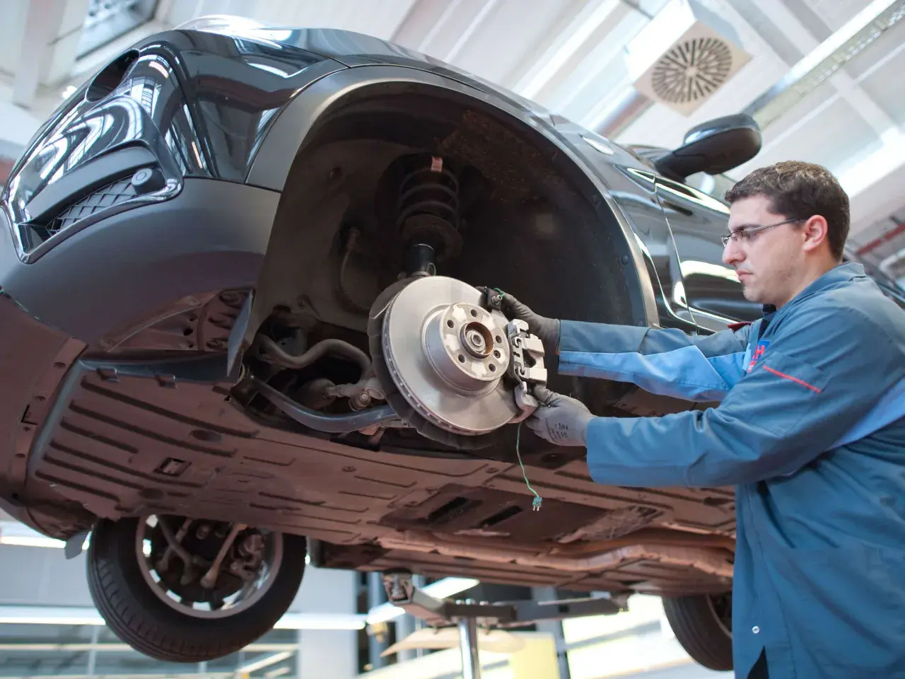 Mechaniker prüft Bremsen eines Autos. Das Quietschen der Bremsen kurz vor Stillstand ist ein Warnsignal für Verschleiß.