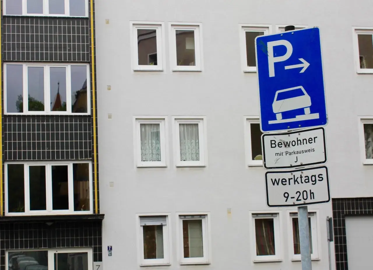 Parken für Bewohner mit Parkausweis werktags 9-20 Uhr, sonst Strafe. Ein blaues Schild mit Auto und Pfeil weist den Weg.