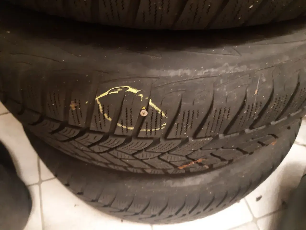 Eine Schraube im Reifen markiert den Schaden, der für die Reifenreparatur vorbereitet wird.