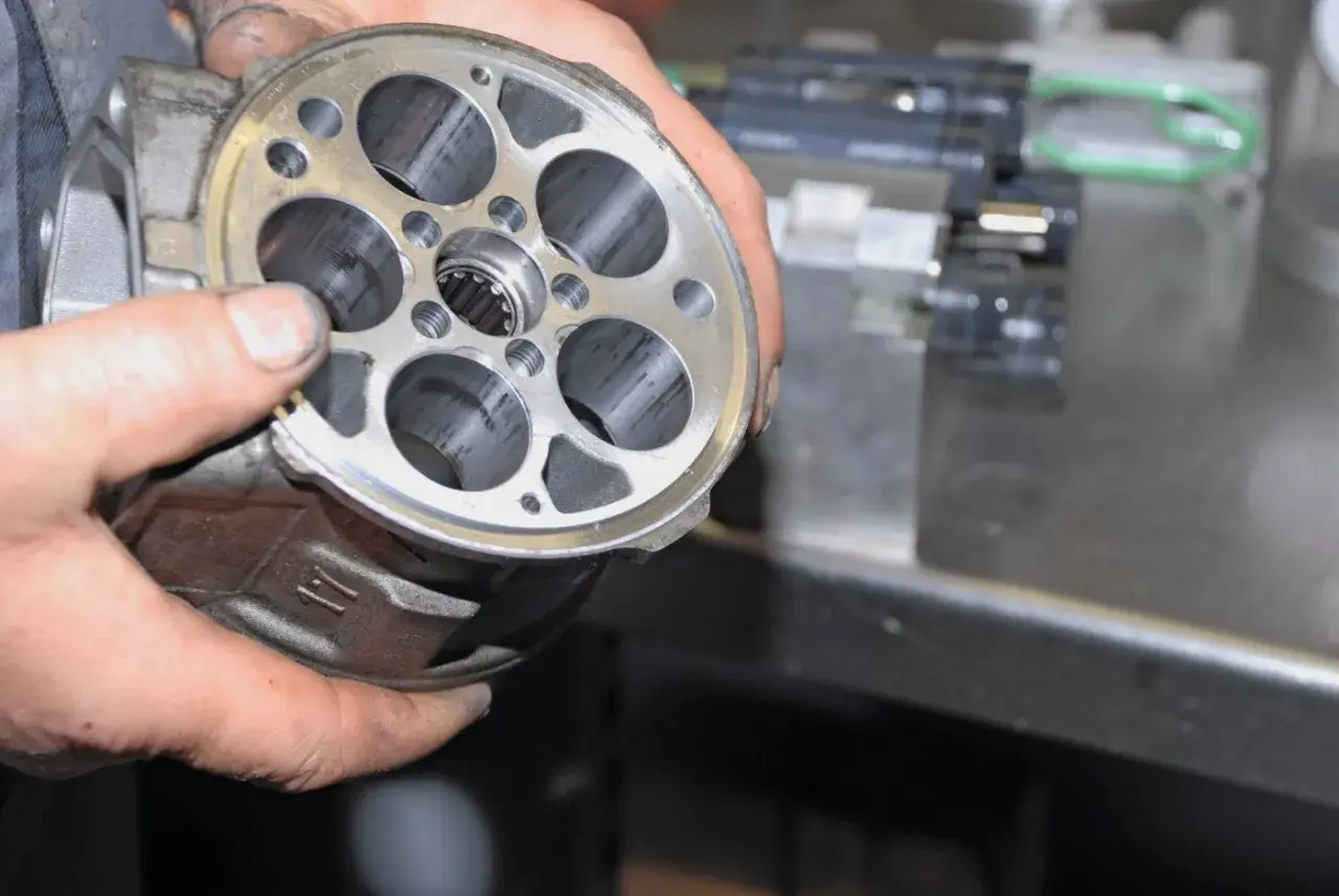 Hände halten einen Klimakompressor zur Überprüfung, ob die Magnetkupplung gewechselt werden muss.