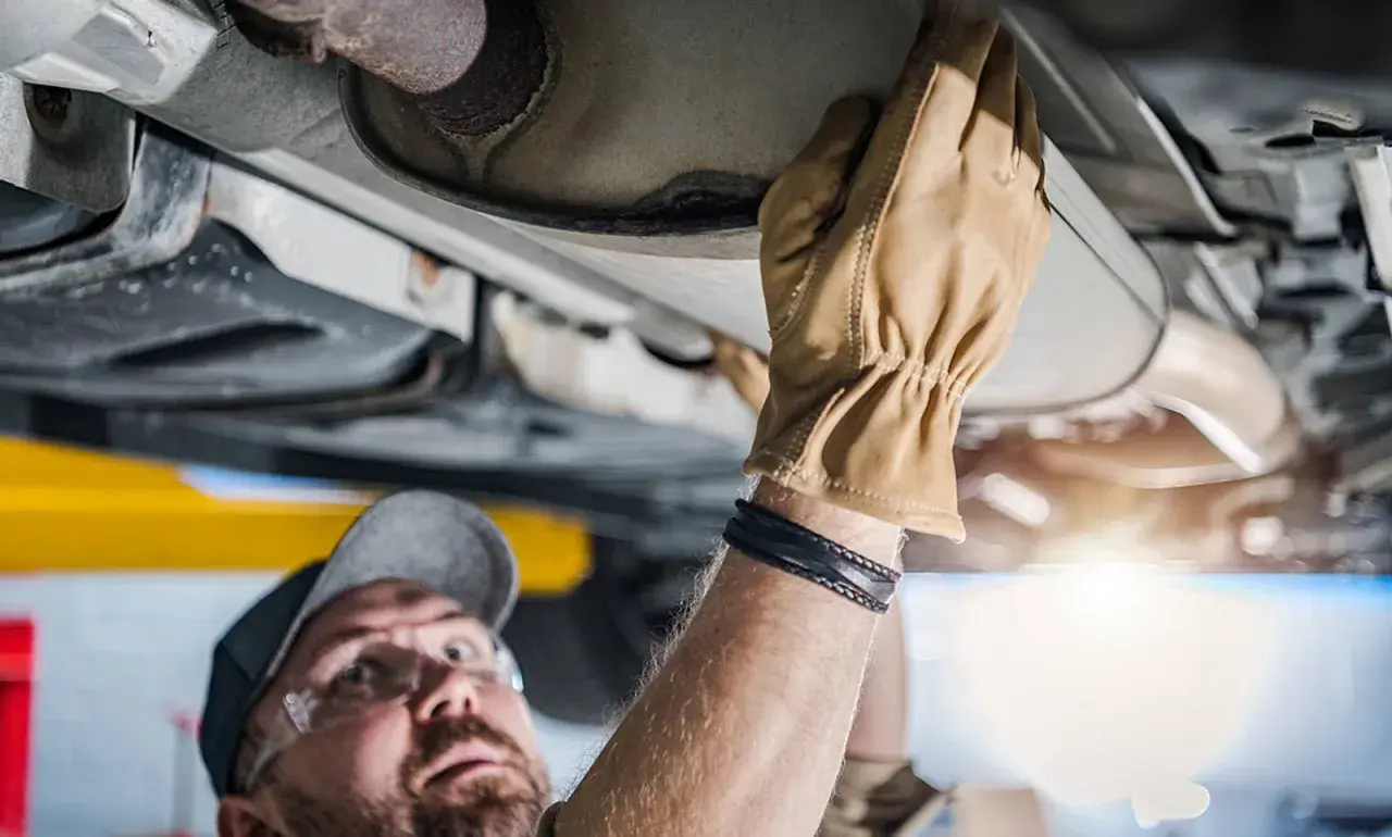 Mechaniker prüft Auspuffanlage. Ein kaputter Katalysator kann das Weiterfahren erschweren.