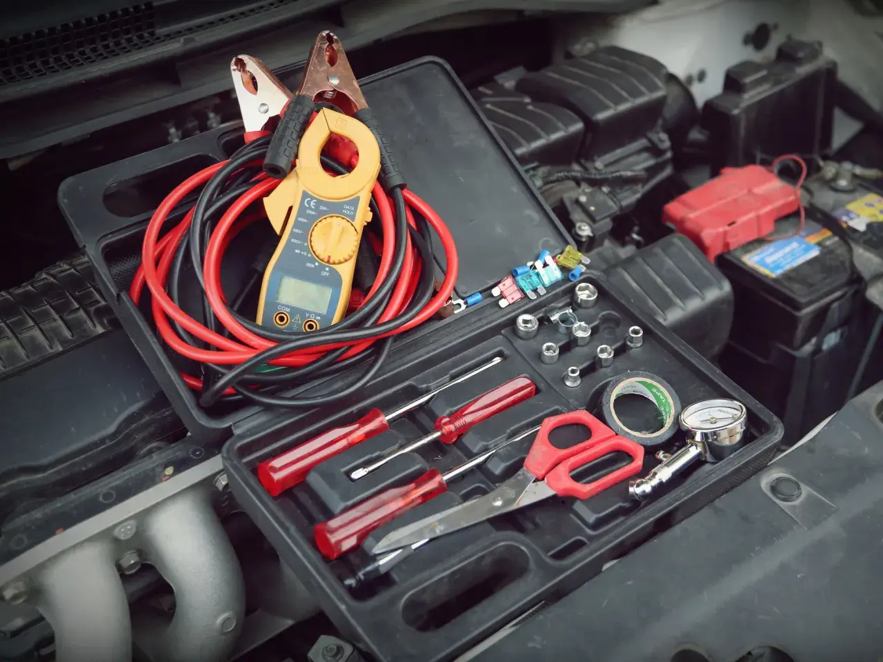 Werkzeugkasten mit Zangenamperemeter, Kabeln und Werkzeugen, bereit, die 12V Batterie zu messen.