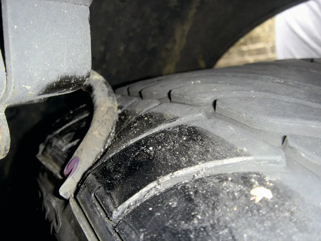 Nahaufnahme eines Reifens mit sichtbaren Rissen und einer verbogenen Metallfeder. Ein **feder gebrochen auto**-Problem, das dringend behoben werden muss.