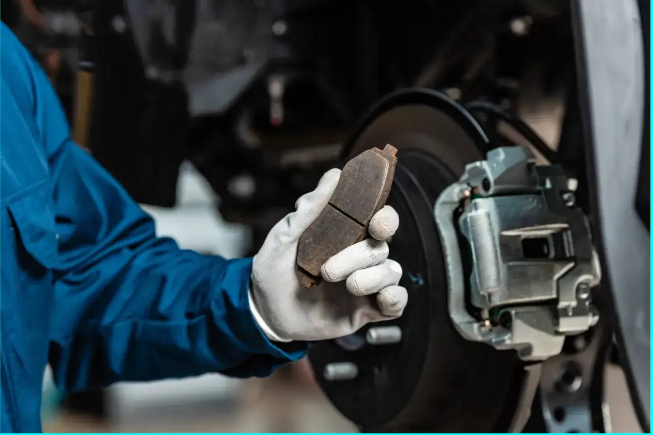 Mechaniker hält abgefahrene Bremsen in der Hand, bereit für den Austausch.