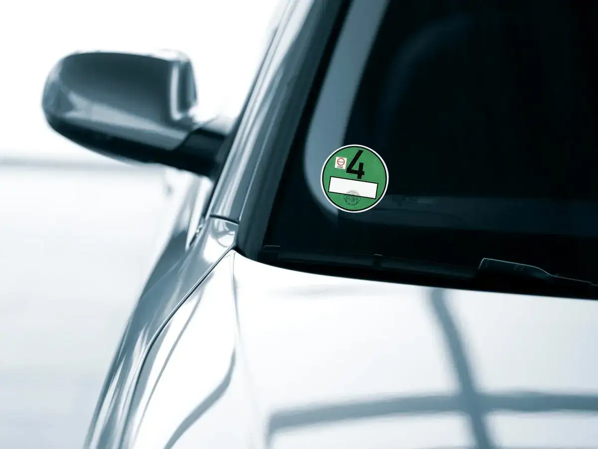 Grüne Umweltplakette mit der Nummer 4, die an der Windschutzscheibe eines Autos angebracht ist.