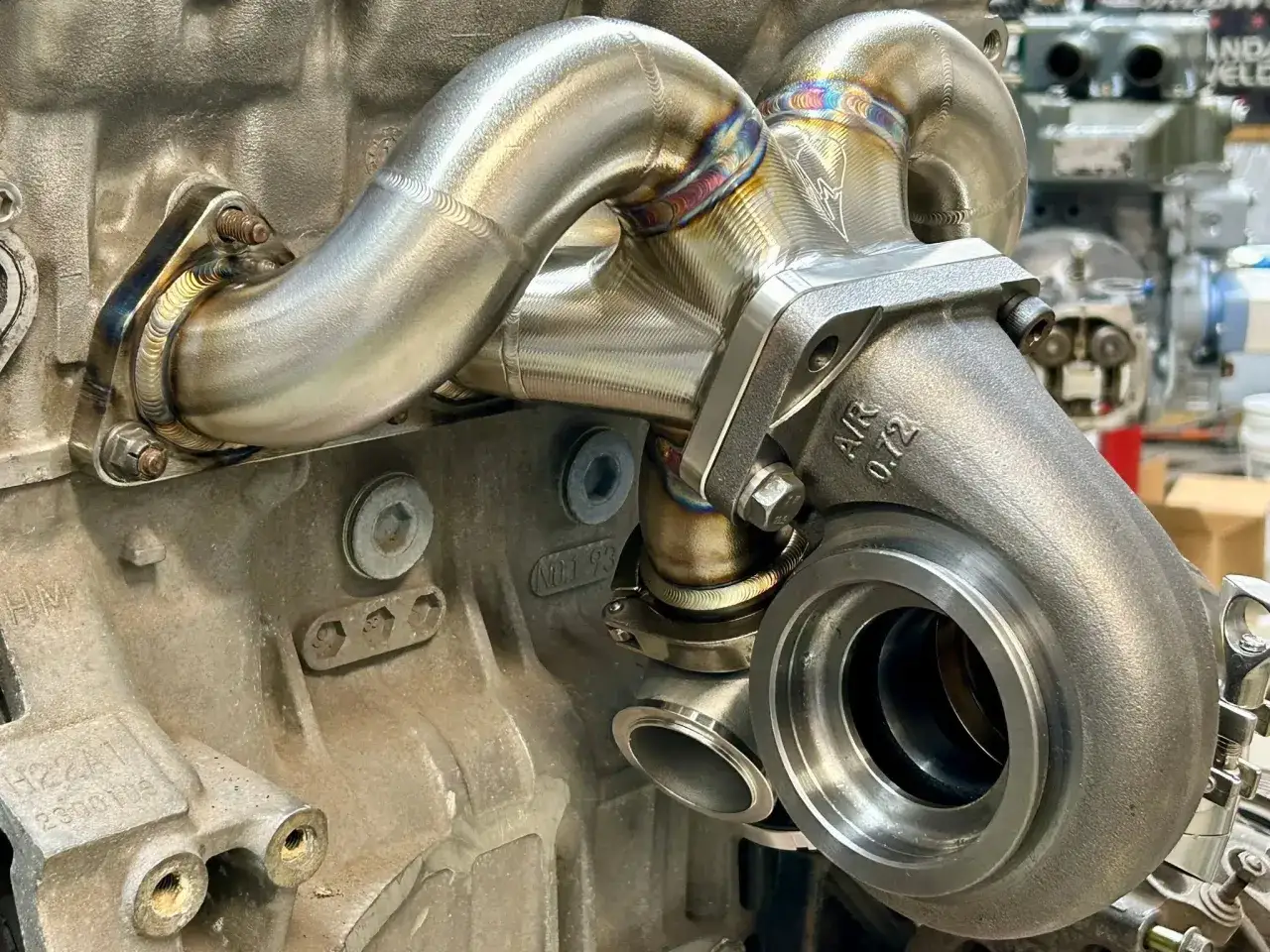 Nahaufnahme eines Turboladers, der an einem Motorblock montiert ist. Die Schweißnähte sind sichtbar. Mögliche Anzeichen für einen turbolader defekt symptome sind Leistungsverlust oder ungewöhnliche Geräusche.