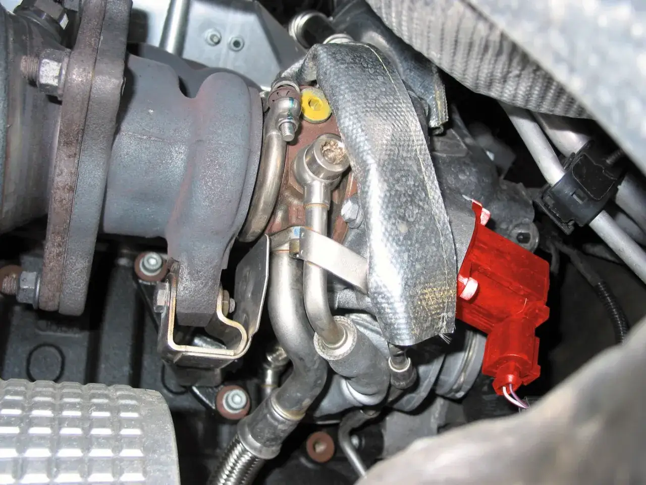 Motorraum mit Turbolader und rot markiertem Bauteil. M&ouml;gliche Symptome bei einem defekten Ladedruckregelventil sind hier zu sehen.