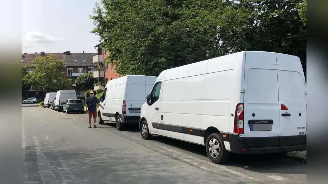 Ein Mann steht neben einer Reihe weißer Lieferwagen, bereit, ein Poolfahrzeug mit nach Hause zu nehmen.