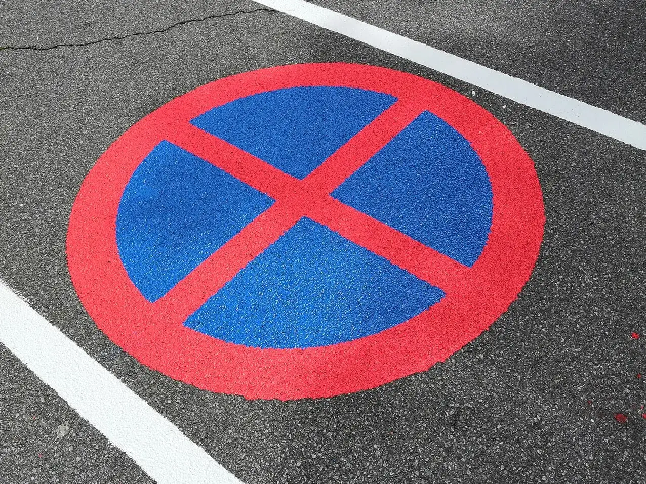 Verkehrszeichen auf Asphalt: Hier darf man nicht parken oder halten. Man muss warten, bis man weiterfahren darf.