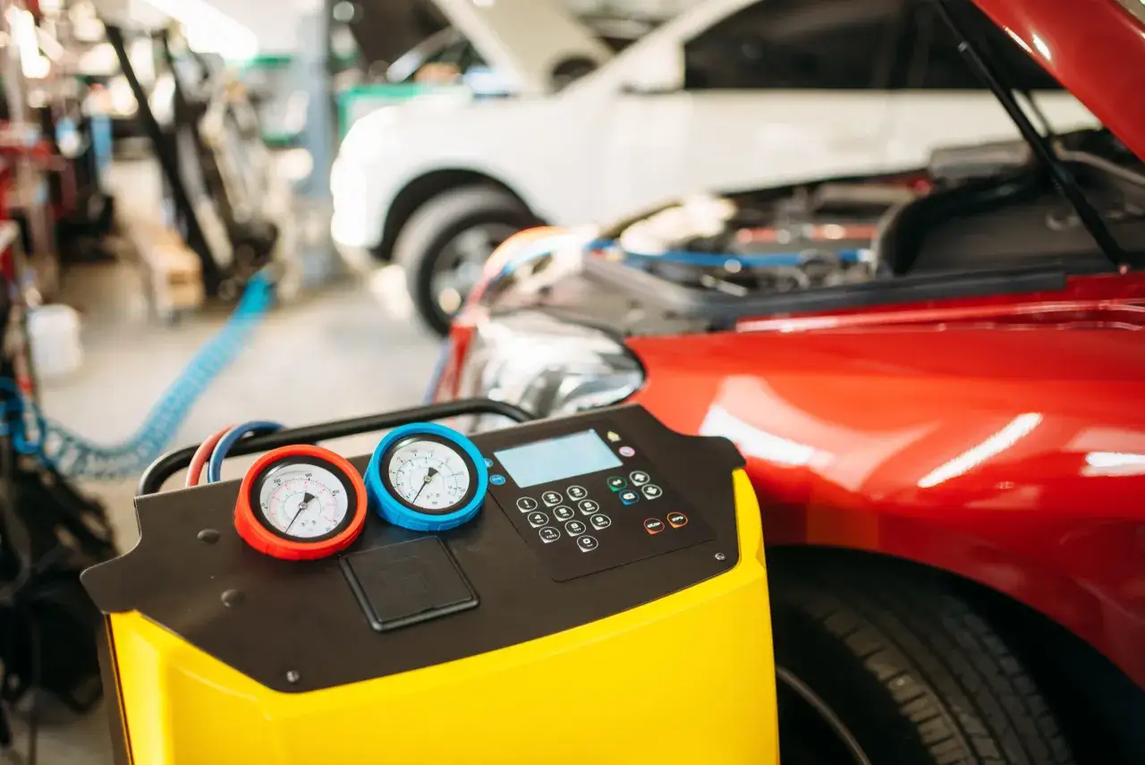 Ger&auml;t zur Klimaanlagenwartung neben einem roten Auto. Die Anzeige zeigt an, dass die klimaanlage funktioniert nicht.