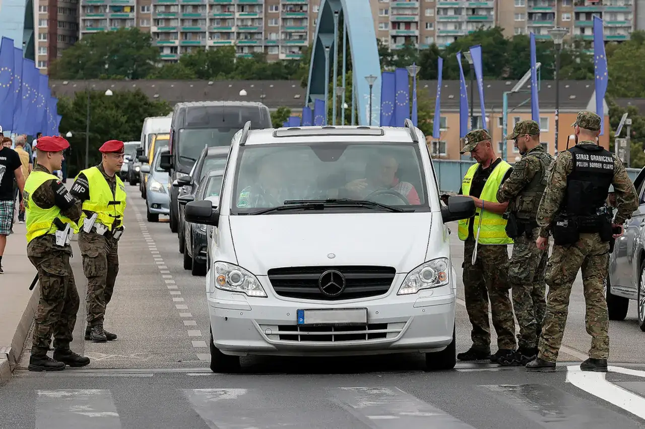 Grenzkontrolle: Polnische Grenzsch&uuml;tzer pr&uuml;fen einen Firmenwagen an der Grenze. EU-Flaggen wehen im Hintergrund.