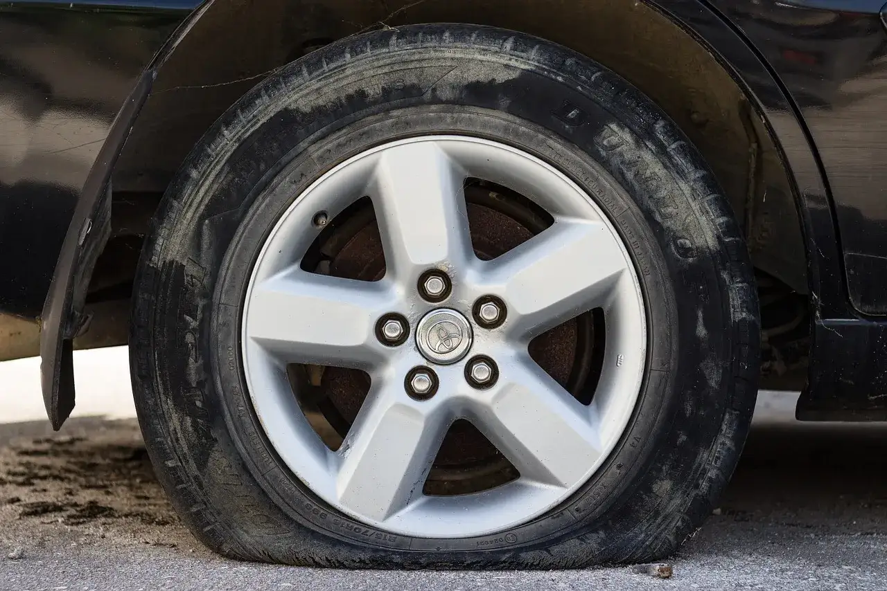 Ein reifen platt was tun? Das Auto steht mit einem platten Reifen auf dem Asphalt.