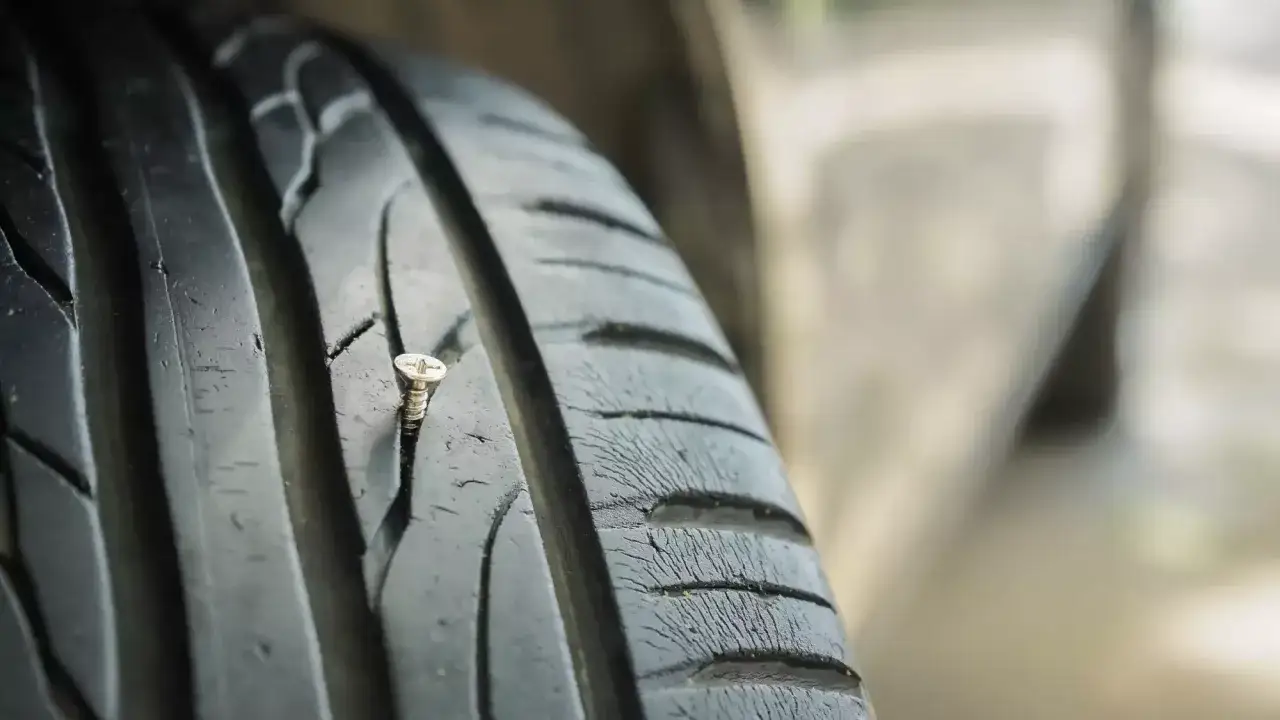 Eine Schraube steckt im Reifen, ein Zeichen f&uuml;r eine Reifenreparatur.