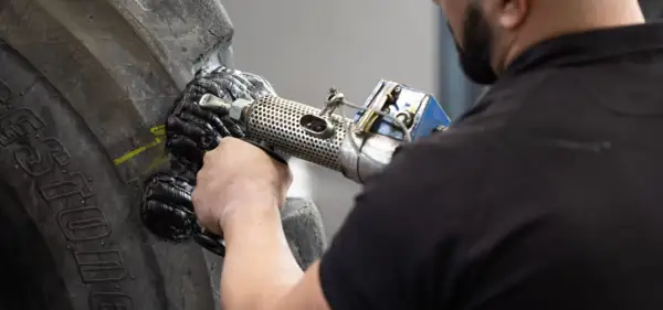 Ein Mechaniker repariert einen Reifen mit einem Vulkanisationsgerät. Die Hitze schmilzt das Gummi, um den Schaden zu beheben.