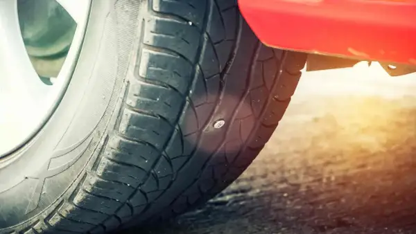 Ein Nagel steckt im Reifen. Das Auto hat einen Platten.