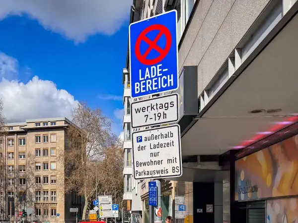 Verkehrsschilder weisen auf eine Ladezone hin, in der werktags von 7-19 Uhr Parken verboten ist. Außerhalb der Ladezeit ist Parken nur für Anwohner mit Parkausweis gestattet.