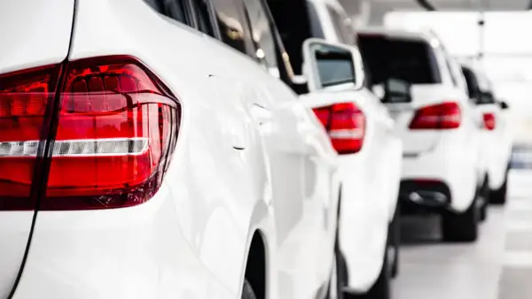 Reihe weißer Autos, bereit, als Poolfahrzeug mit nach Hause genommen zu werden.