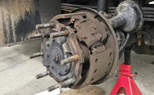 Detailaufnahme einer Trommelbremse mit freiliegenden Bremsbelägen und Radbolzen. Die Handbremse einstellen erfordert hier präzises Arbeiten.