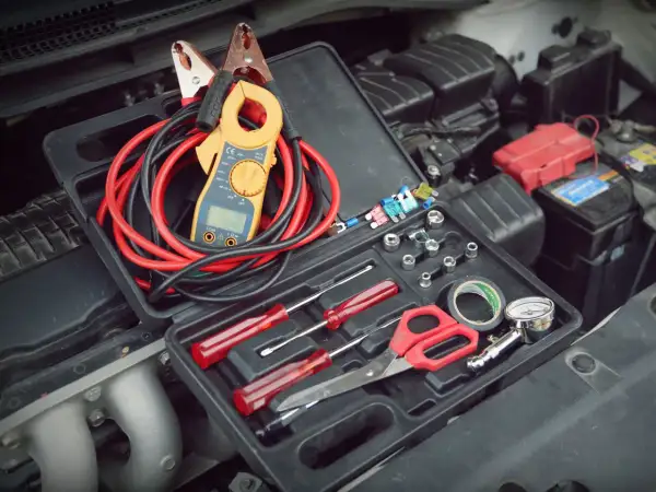 Werkzeugkasten mit Zangenamperemeter, Kabeln und Werkzeugen, bereit, die 12V Batterie zu messen.