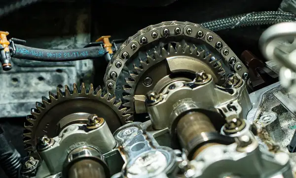 Nahaufnahme eines Motors mit Zahnrädern und Steuerkette. Ein Mechaniker prüft, wann steuerkette wechseln.